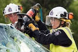 A firefighter using an electric tool to cut open the windscreen of a car.