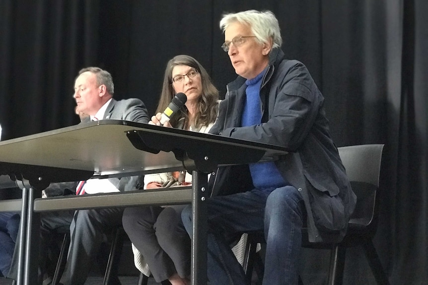 Man sits at a desk speaking into a microphone