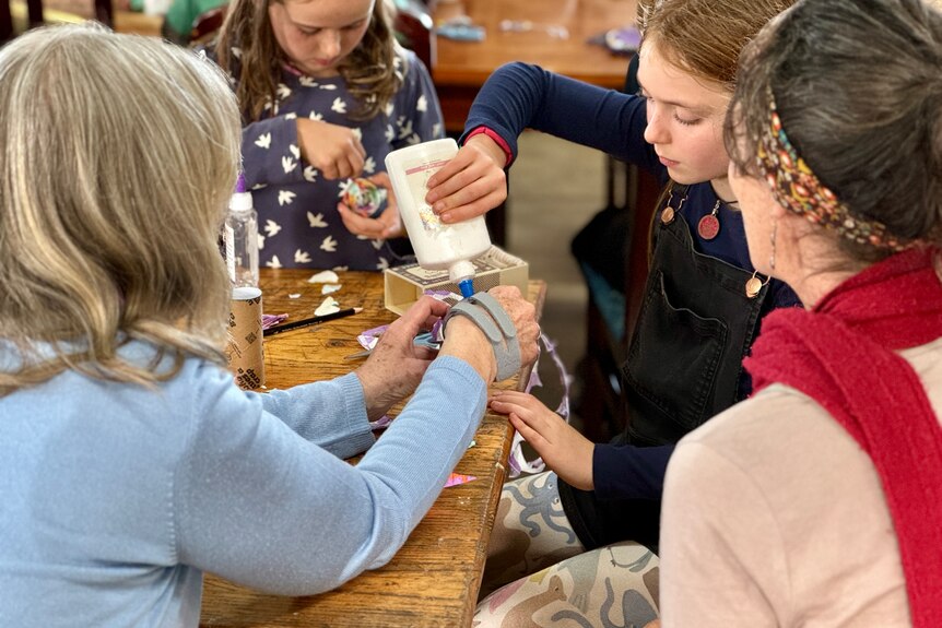 Woman helps children with craft