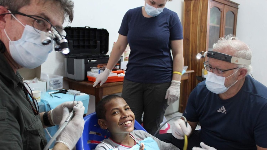 An East Timorese boy gives a thumbs up after dental care from Dr Malcolm Campbell, nurse Bec Apps and Dr Mark Tuffley.