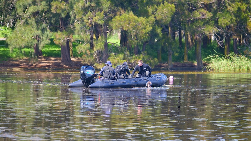 Police divers on a boat on a lake. 