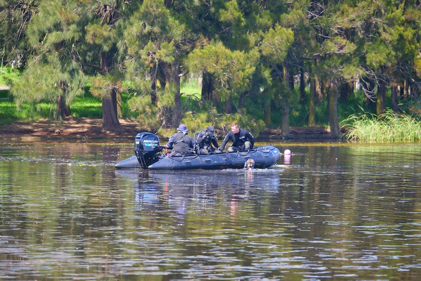 Police divers on a boat on a lake. 