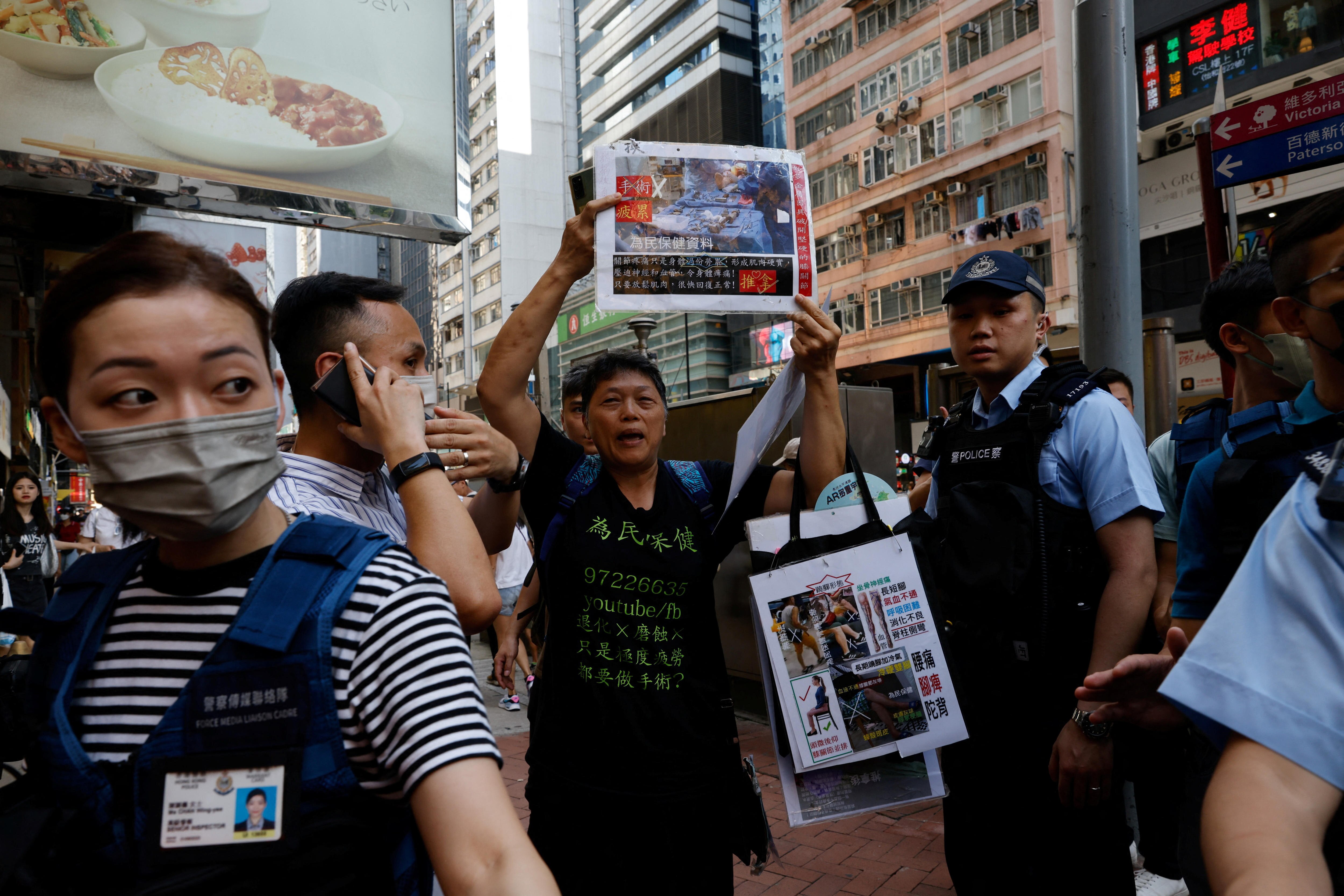 A woman holds up a sign while standing next to a police officer. 