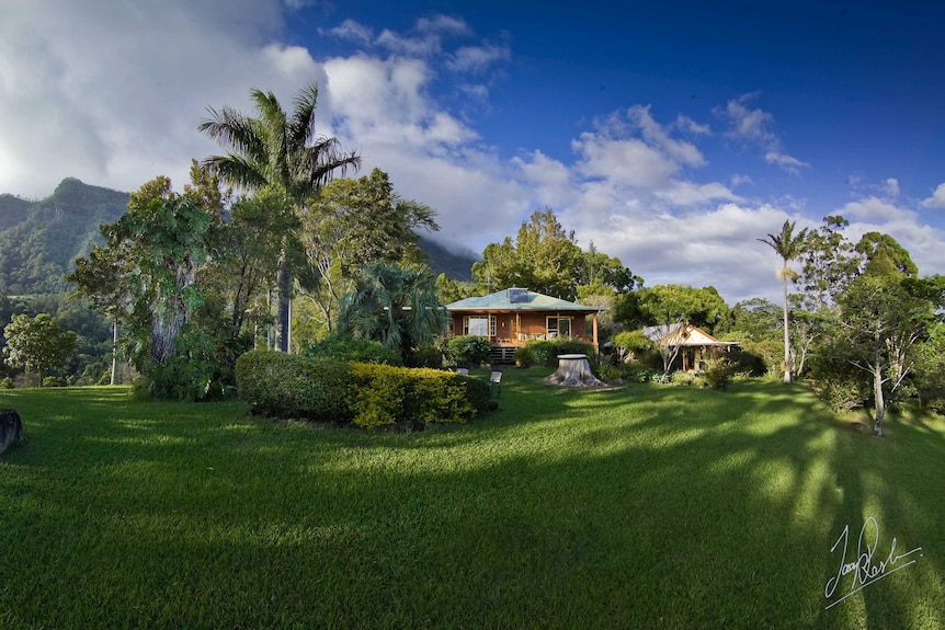 A house on a property with a mountain backdrop and blue sky.