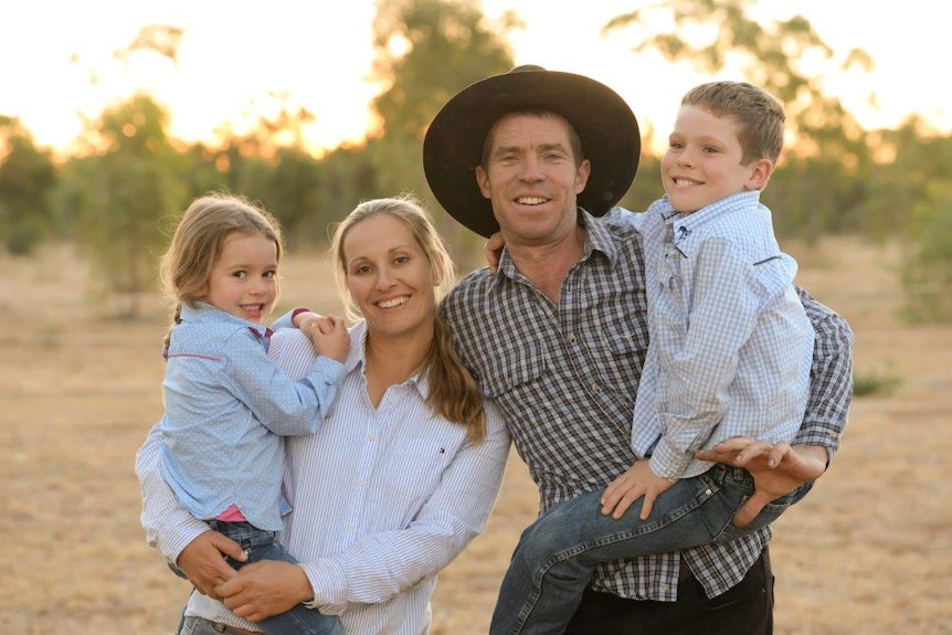 Megan Munchenberg, her husband, and two children standing with a yellow sunset behind them.