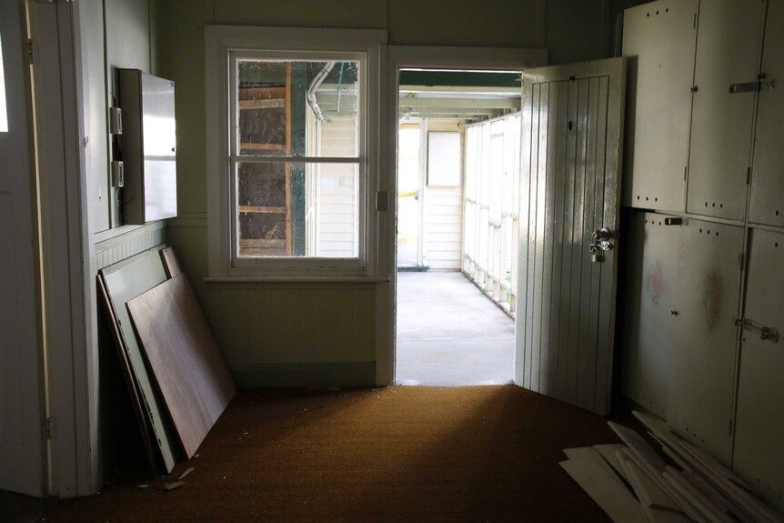 A run-down room inside an old army hospital in Tasmania. Scrap wood lays in a pile near the door.