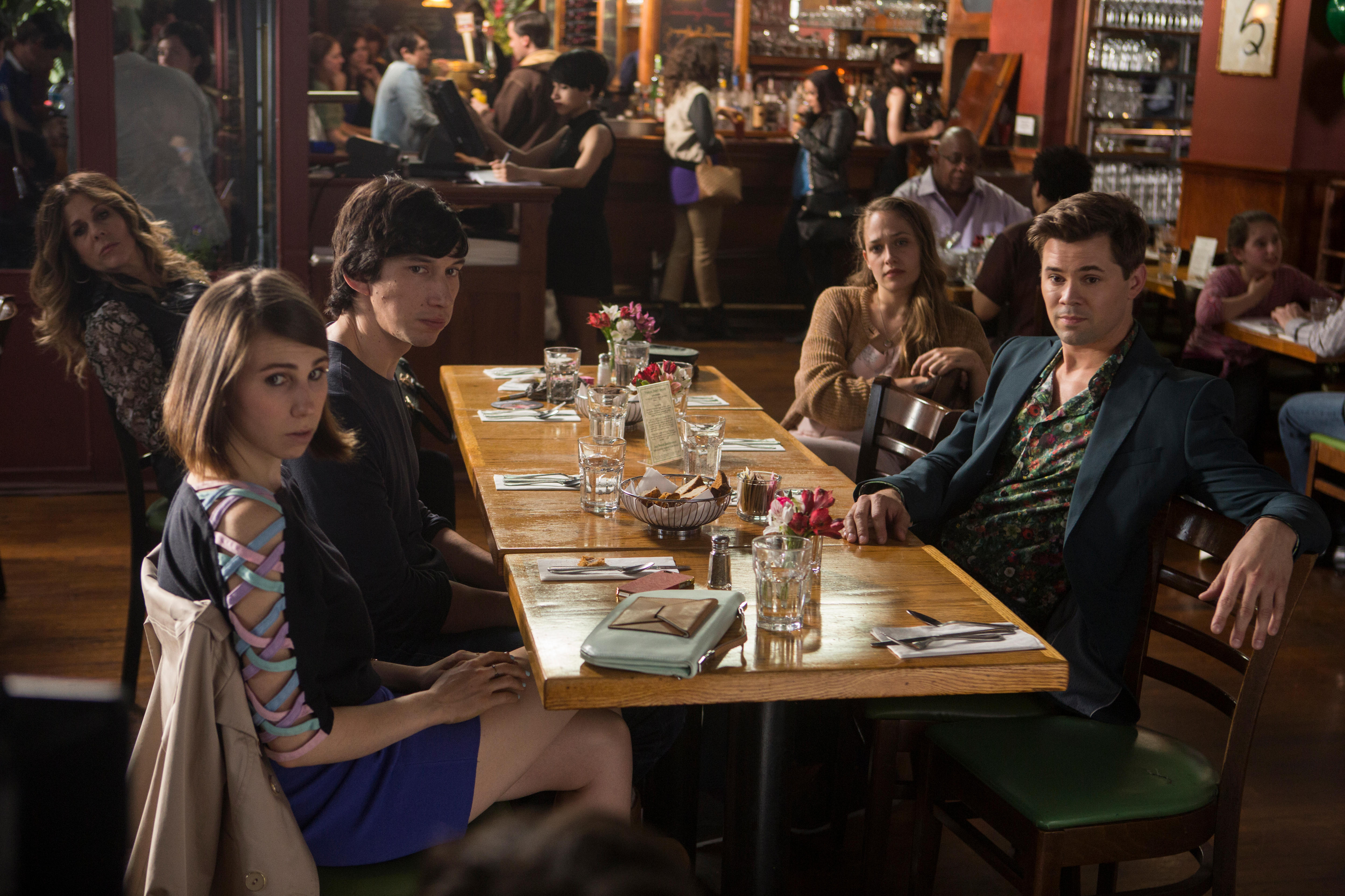 Two young men and two young women sitting at a dining table which is set but has no food on it