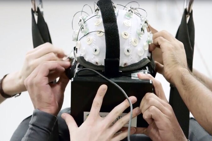 A person wears a cap lined with electrodes to record their brain activity.
