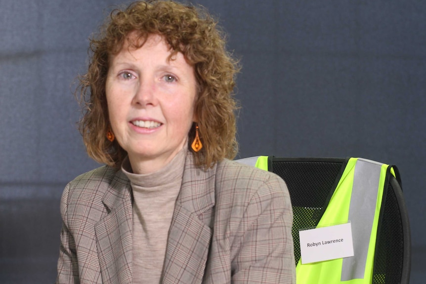 portrait shot of Robyn Lawrence with high viz jacket hanging on chair