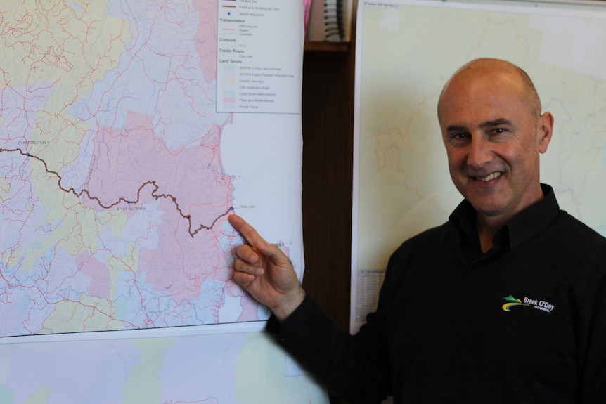 A man points to a mountain bike trail map