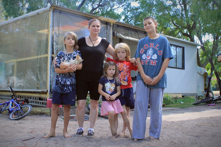 A woman, a young girl and three boys outside a caravan.