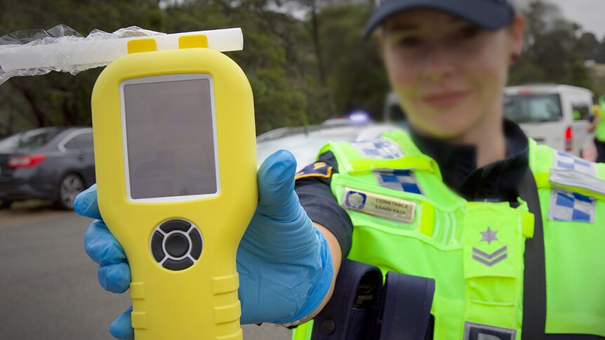 Female Tasmania Police officer with breathalyser at random testing station