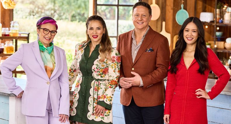 Cal Wilson, Rachel Khoo, Darren Purchese and Natalie Tran smile and pose together in the Bake Off kitchen.