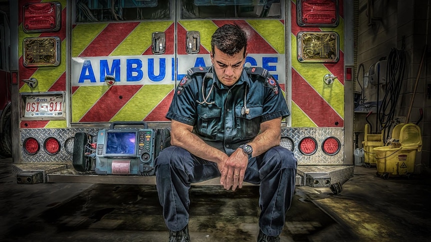 A photo in drawing style of a paramedic in uniform sitting on the end of his ambulance truck, looking down.