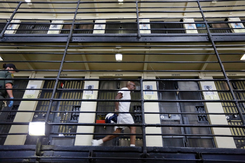 A handcuffed man walks down a hallway on death row.