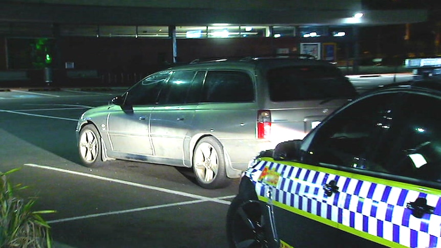 A station wagon parked in a shopping centre carpark at Laverton at night.