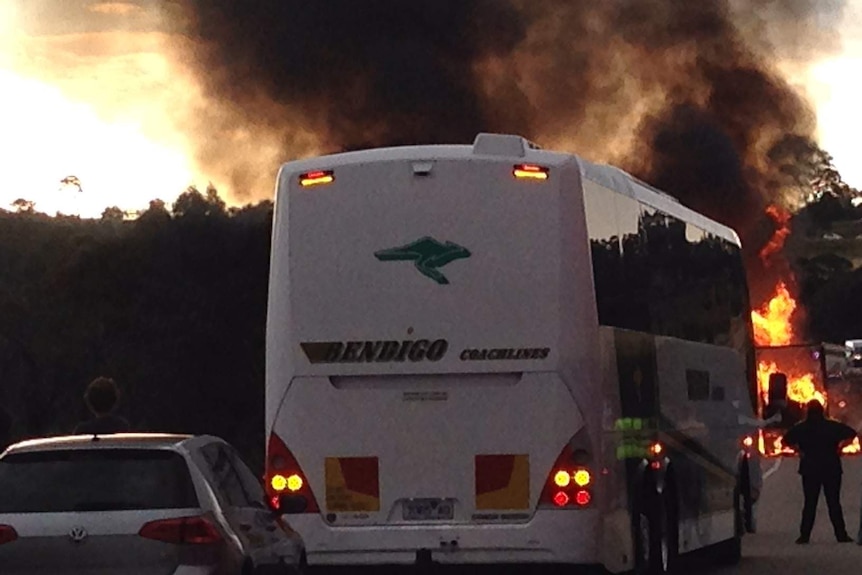 People and police watch as a B-Double truck burns.