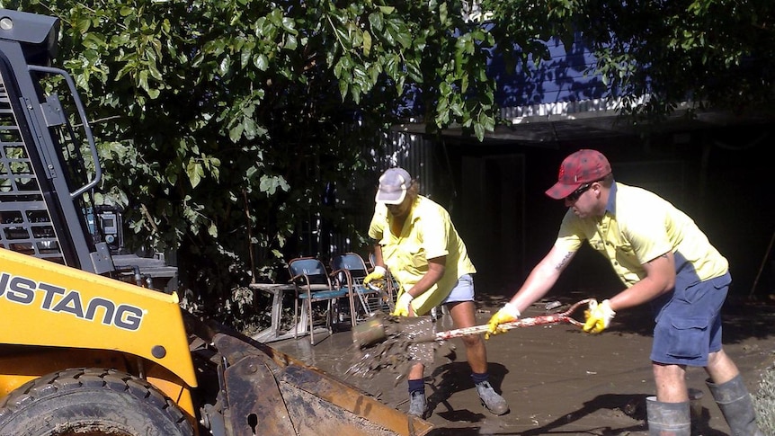 People shovel mud and sludge on Beck Street in the Brisbane suburb of Paddington.