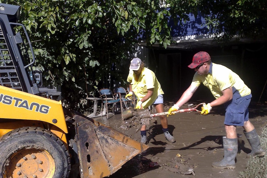Clean-up underway: people shovel mud and sludge on Beck Street in the Brisbane suburb of Paddington.
