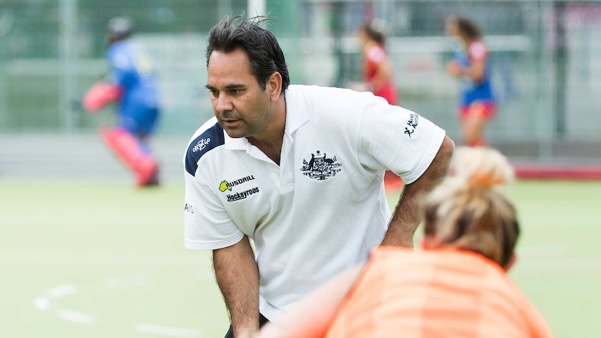 Hockeyroos coach Paul Gaudoin on the field with a player in the foreground.