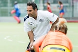 Hockeyroos coach Paul Gaudoin on the field with a player in the foreground.