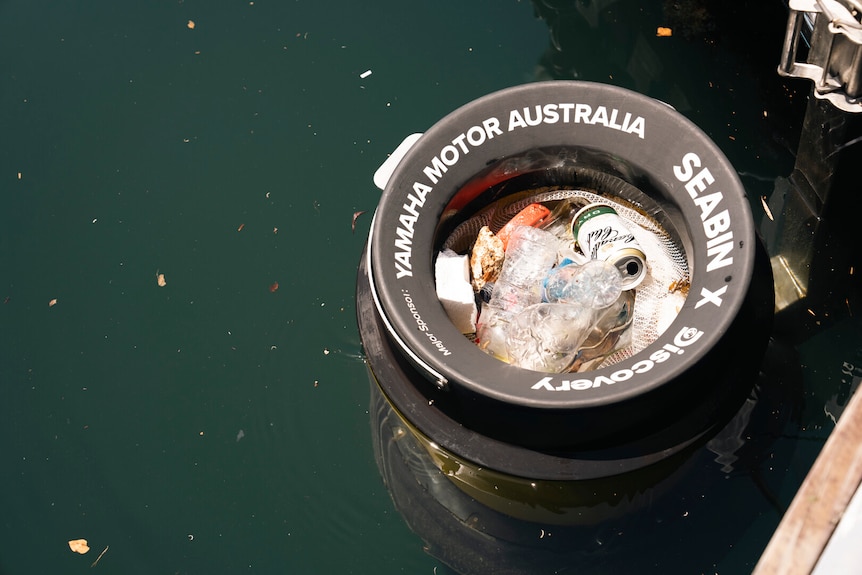 A bin filled with rubbish floating on the surface of water
