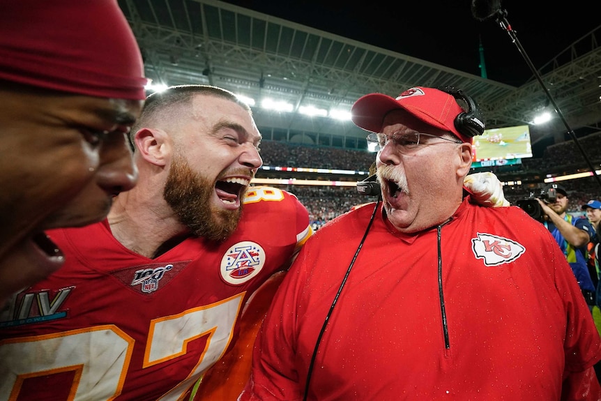 Andy Reid yells while Travis Kelce screams in delight. They are arm in arm.