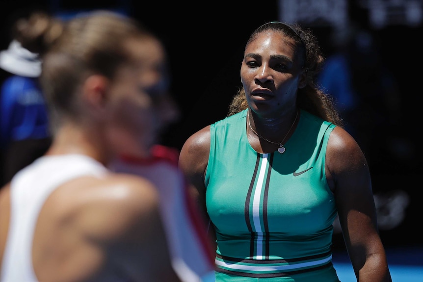 Serena Williams walks toward Karolina Pliskova, blurred in the foreground, during their Australian Open tennis match.