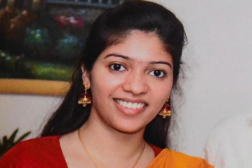 A photo of Nimisha, a young Indian woman in a red and orange sari