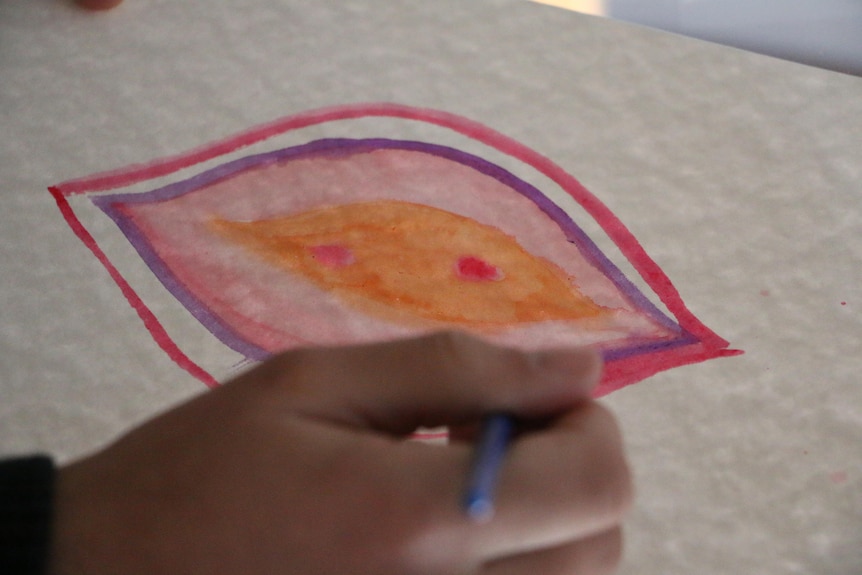 An artist at work on a colourful painting of a vagina.
