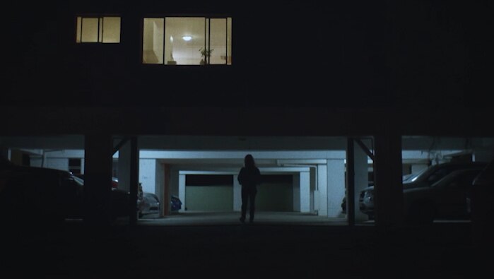 Blonde woman exiting apartment building at night