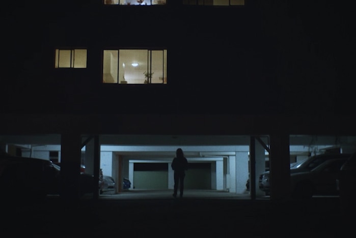 Blonde woman exiting apartment building at night