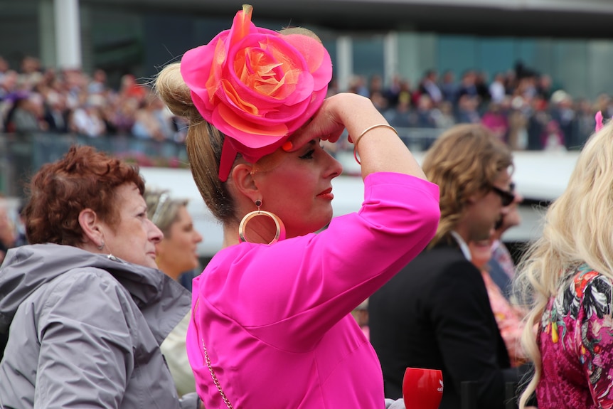 A side profile of a woman wearing a bright pink suit and gold earring.