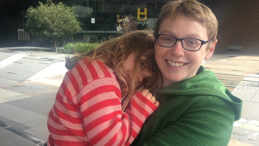 Miranda Cumpston holds her daughter Winifred who naps on her shoulder