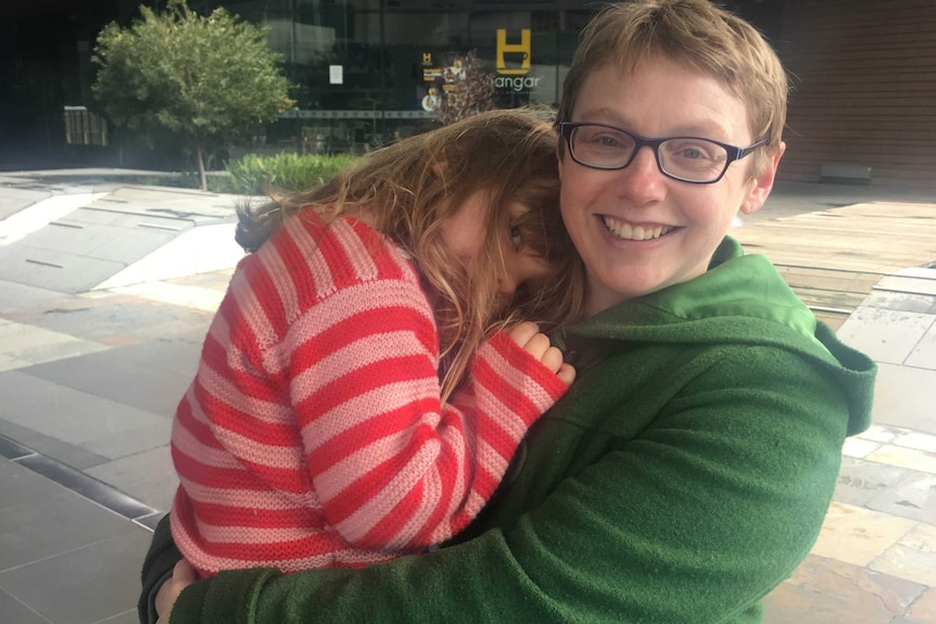 Miranda Cumpston holds her daughter Winifred who naps on her shoulder