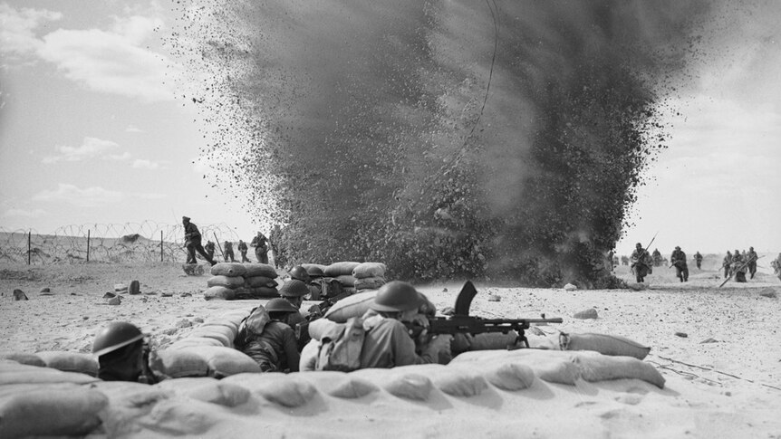 Black and white photo of a machine trench in the foreground and an explosion in the background
