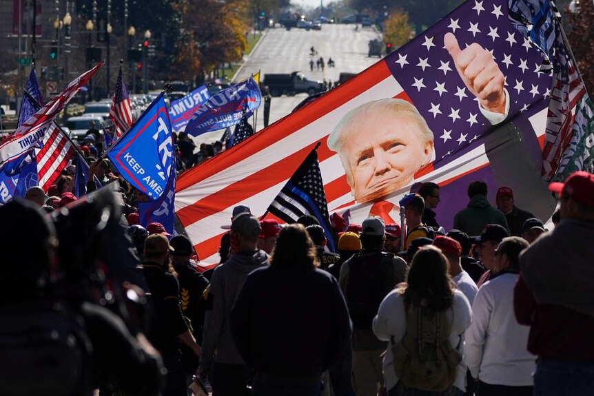 Supporters of President Donald Trump hold a banner with Trump's picture in front of a US flag.