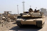 An army tank drives alongside destroyed buildings at Mosul airport.
