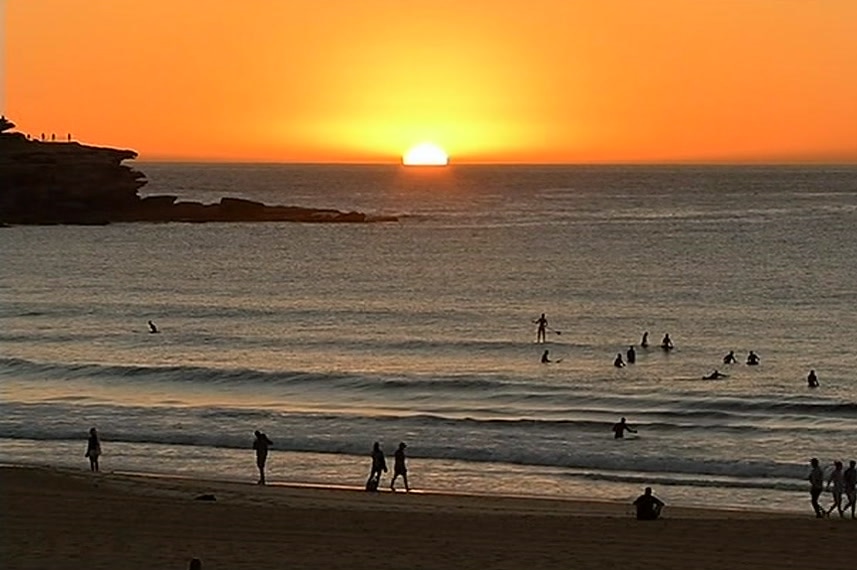 The sun rising above the horizon at Bondi Beach.