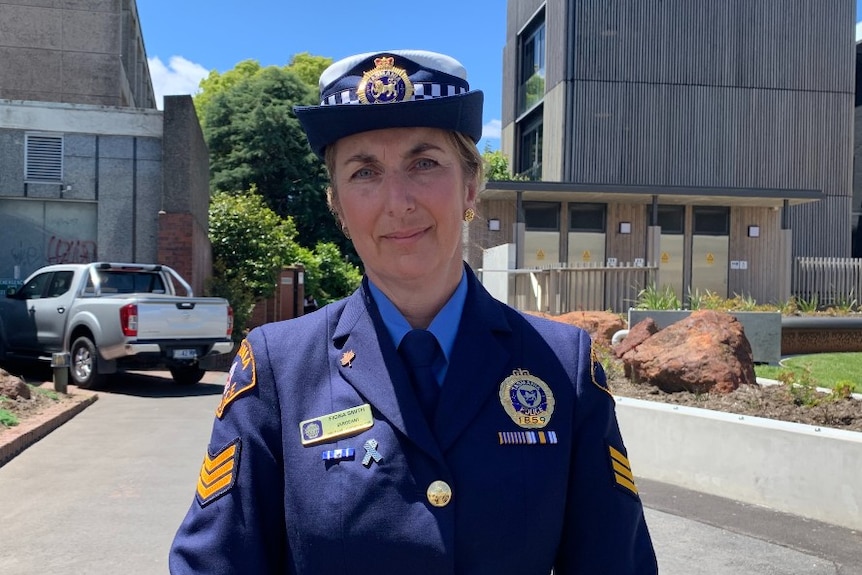 A police woman in uniform stands in front of a building