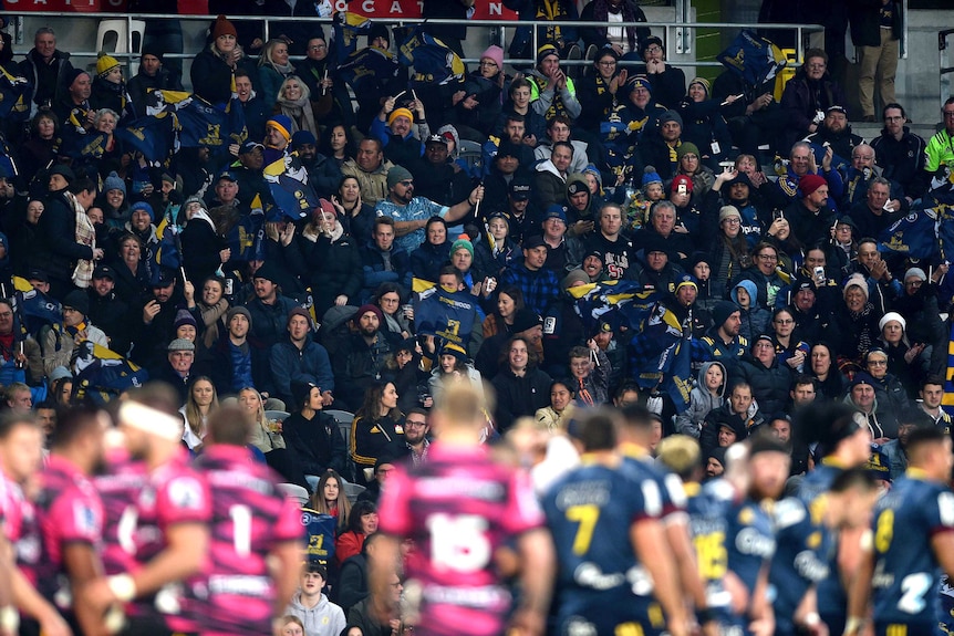 Fans applaud as players line up in the foreground