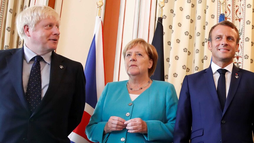 Boris Johnson looks across as Angela Merkel and Emmanuel Macron stare ahead