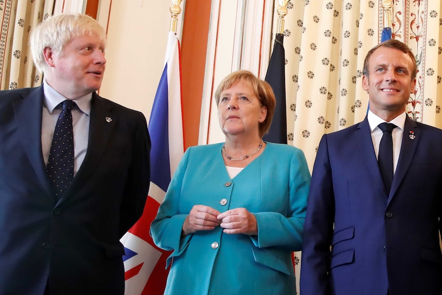 Boris Johnson looks across as Angela Merkel and Emmanuel Macron stare ahead
