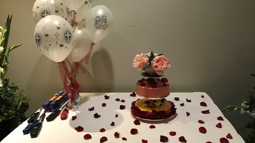 The wedding cake with balloons and petals on the table