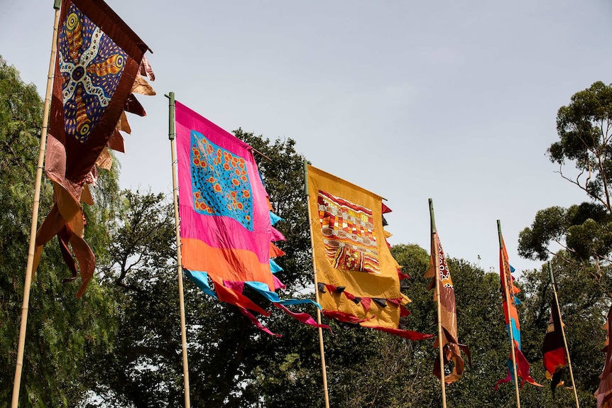 Colourful flags stand against a tree line