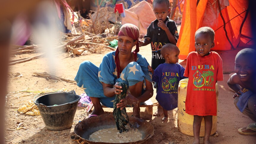 A woman washes clothes in a dish.