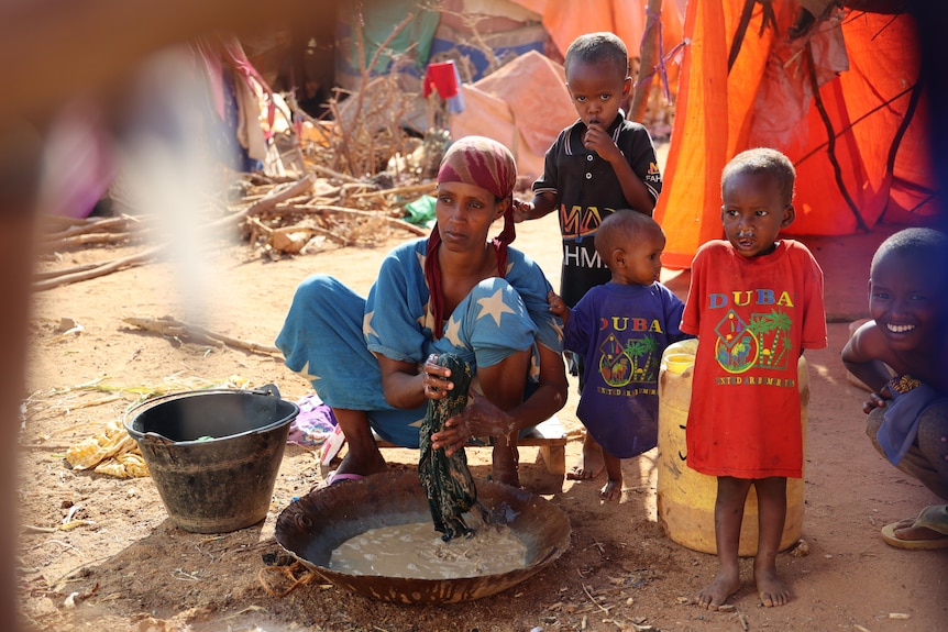 A woman washes clothes in a dish.