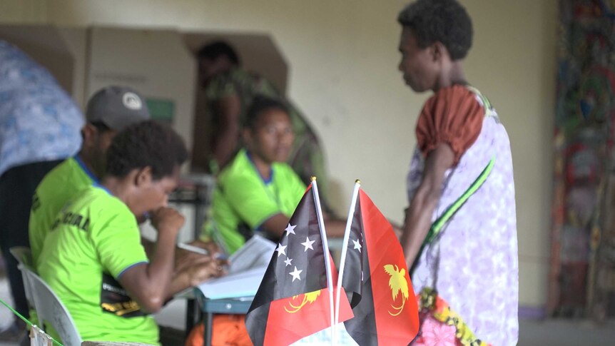 A woman wearing traditional PNG dress casts her ballot at a high school in Port Moresby.