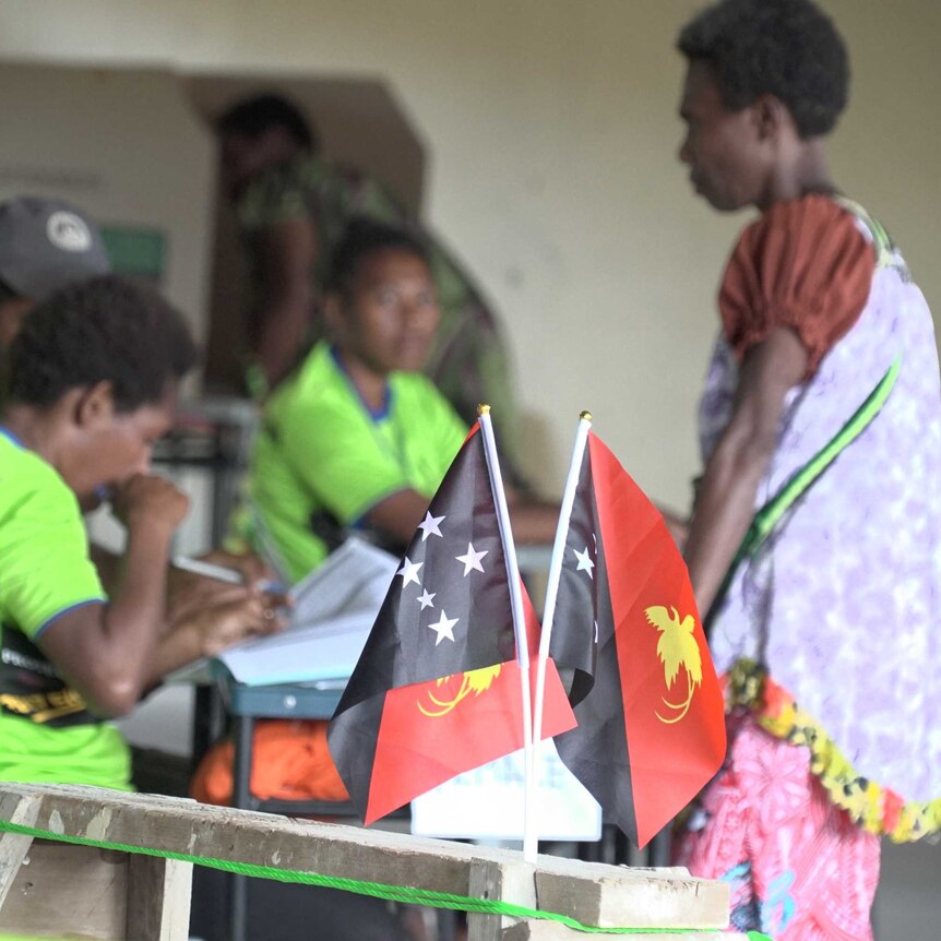 A woman wearing traditional PNG dress casts her ballot in a high school in port moresby
