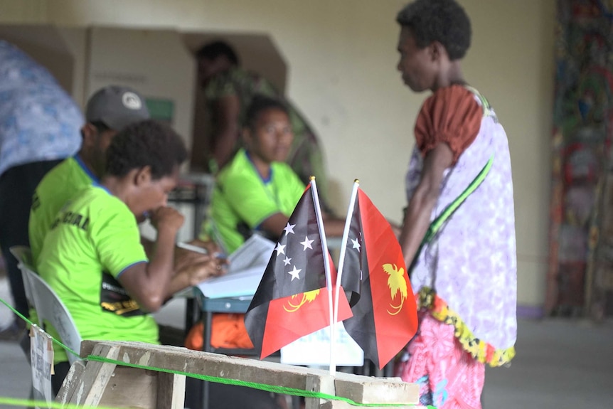 A woman wearing traditional PNG dress casts her ballot at a high school in Port Moresby.